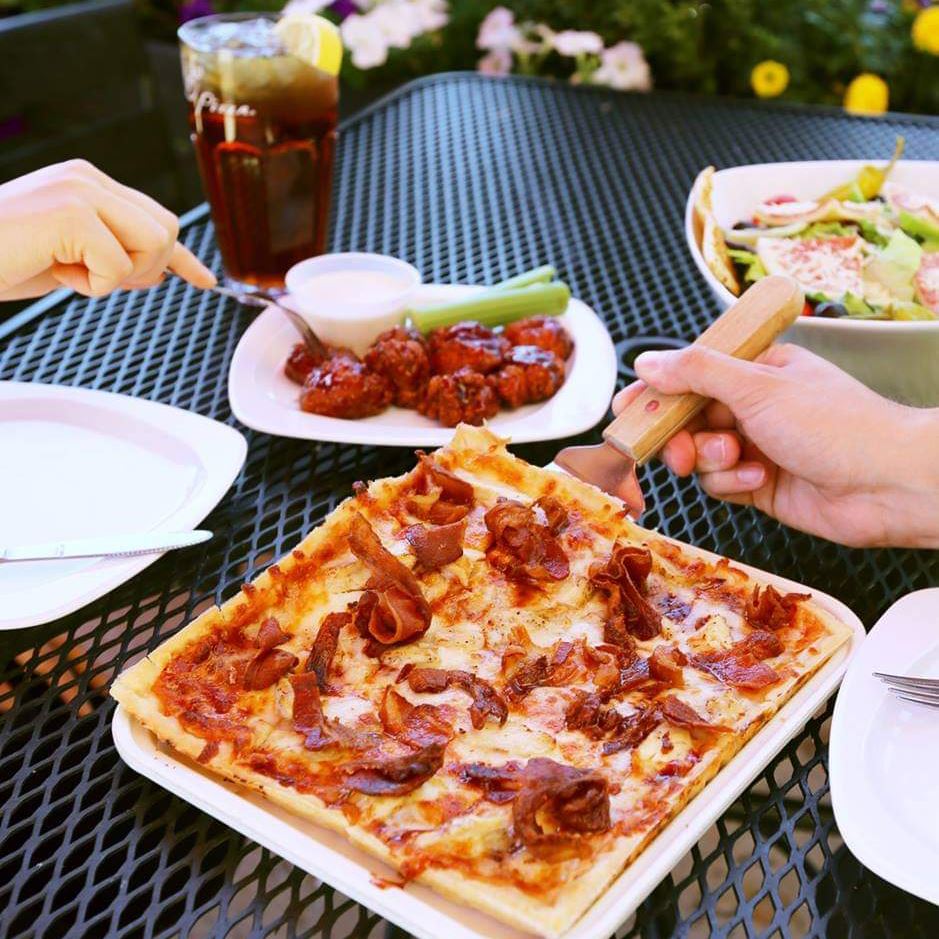 Table with pizza, buffalo wings, soda and salad