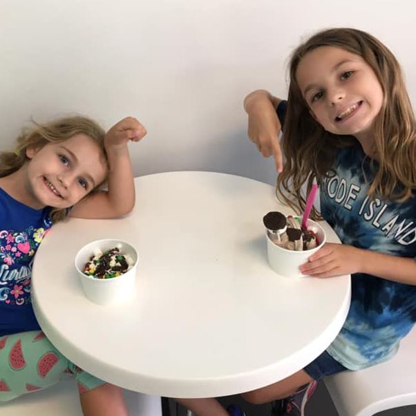 Two children enjoying their ice cream with toppings at Sweet Frog