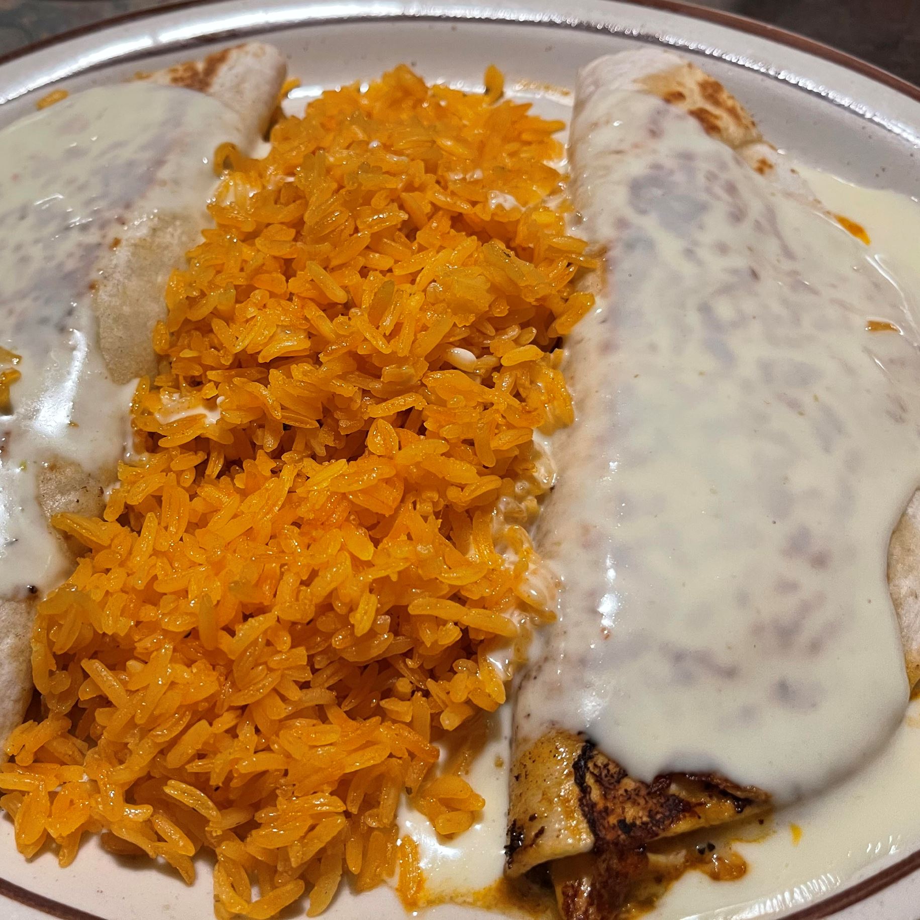 Tortillas covered with a cheese sauce separated by rice