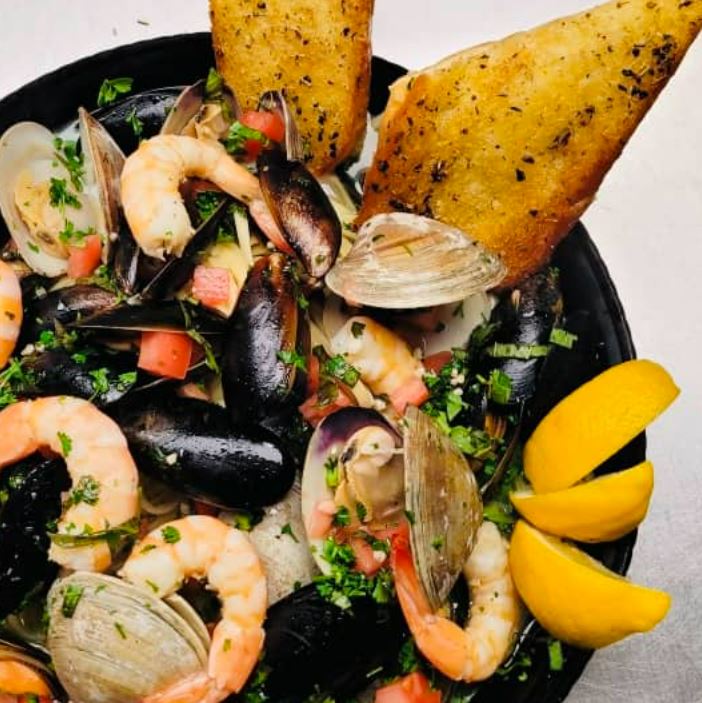 Clams, oysters, shrimp, lemon and bread in a bowl