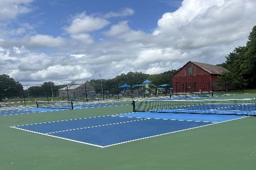 Pickleball courts at Hallowing Point Park with playground and barns in background